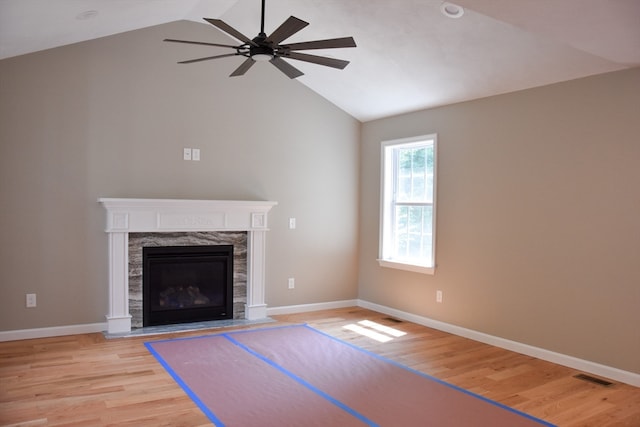 unfurnished living room featuring vaulted ceiling, a premium fireplace, ceiling fan, and light hardwood / wood-style flooring