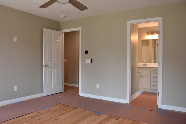 unfurnished bedroom featuring sink, light hardwood / wood-style flooring, ensuite bathroom, and ceiling fan