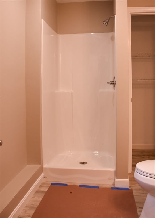 bathroom featuring walk in shower, wood-type flooring, and toilet