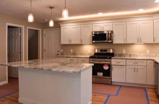 kitchen featuring white cabinets, a kitchen island, appliances with stainless steel finishes, and light wood-type flooring