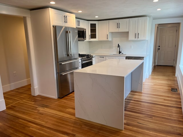 kitchen featuring stainless steel appliances, sink, light wood-type flooring, and white cabinets