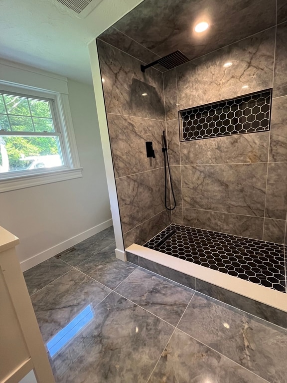 bathroom with tiled shower and vanity