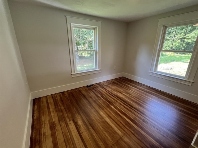 unfurnished room with wood finished floors, a wealth of natural light, and baseboards