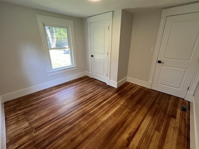 unfurnished bedroom with visible vents, dark wood finished floors, and baseboards