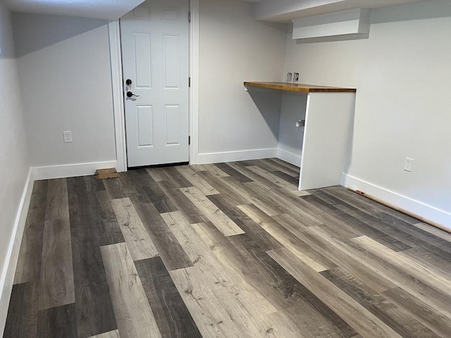 below grade area with baseboards and dark wood finished floors