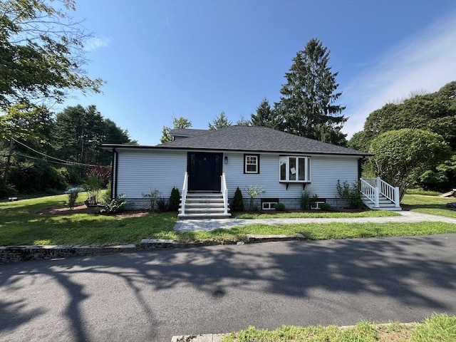 view of front of house featuring entry steps, a front lawn, and roof with shingles