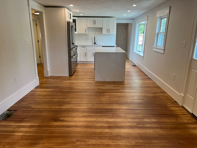 kitchen featuring white cabinets, hardwood / wood-style flooring, a center island, stainless steel refrigerator, and sink