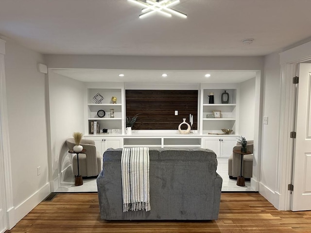 living area with baseboards, wood finished floors, and built in features