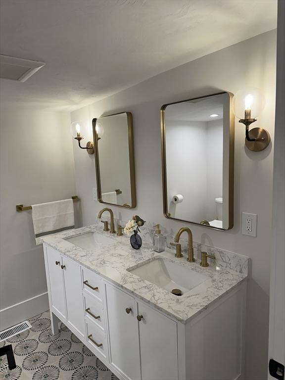 bathroom with tile patterned floors, visible vents, a sink, and double vanity