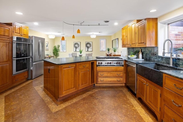 kitchen with stainless steel appliances, brown cabinets, a sink, and a peninsula