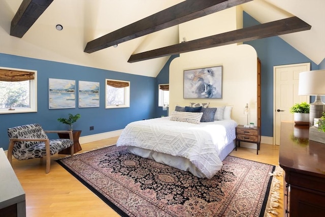 bedroom featuring lofted ceiling with beams, multiple windows, and baseboards