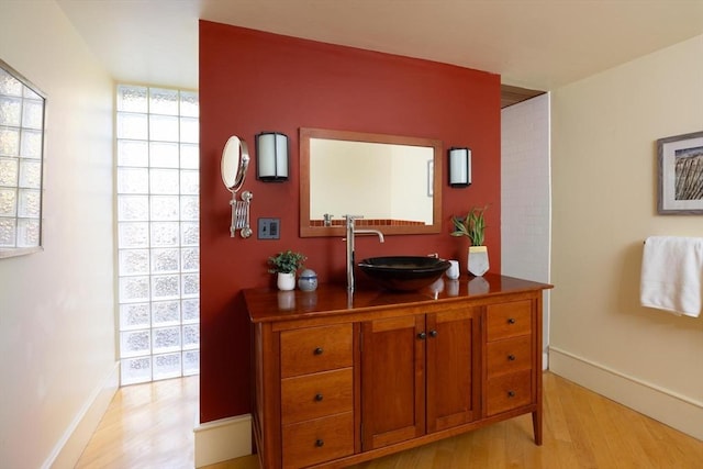 interior space with a sink, light wood-style flooring, and baseboards