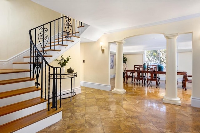 staircase featuring ornate columns, baseboards, and arched walkways