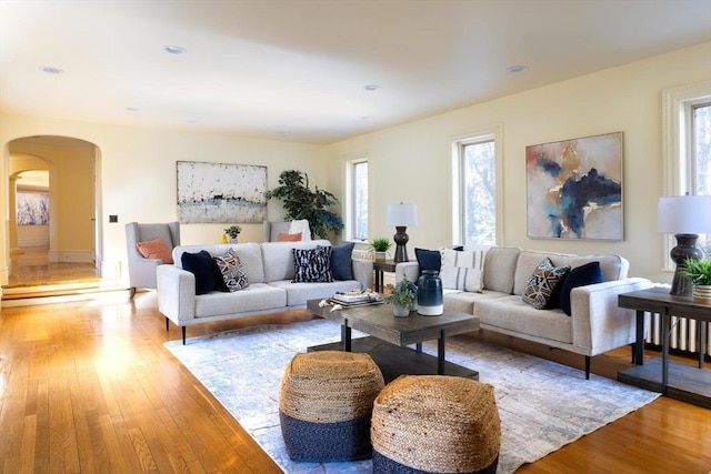 living room with light wood-type flooring, arched walkways, and recessed lighting