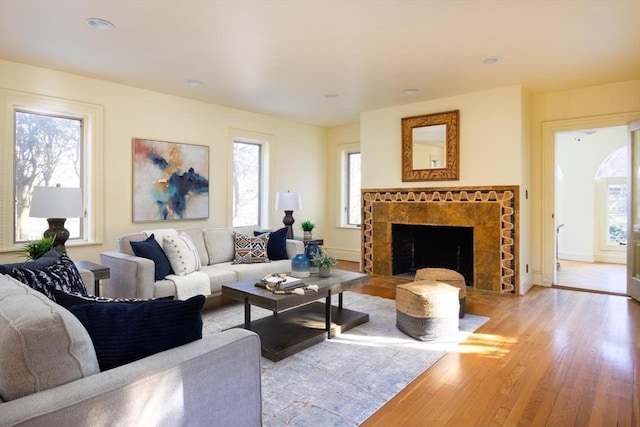 living area featuring hardwood / wood-style floors, a tiled fireplace, recessed lighting, and baseboards