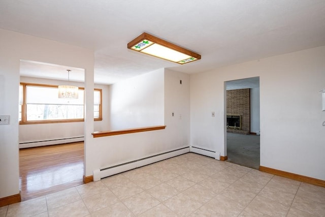 unfurnished room with a baseboard heating unit, a chandelier, a fireplace, and baseboards