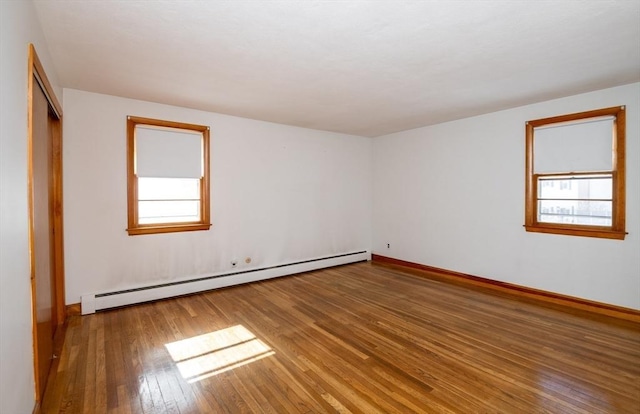 empty room with hardwood / wood-style flooring, baseboards, and a baseboard heating unit