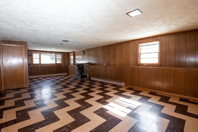 interior space featuring wood walls, baseboard heating, a fireplace, and tile patterned floors