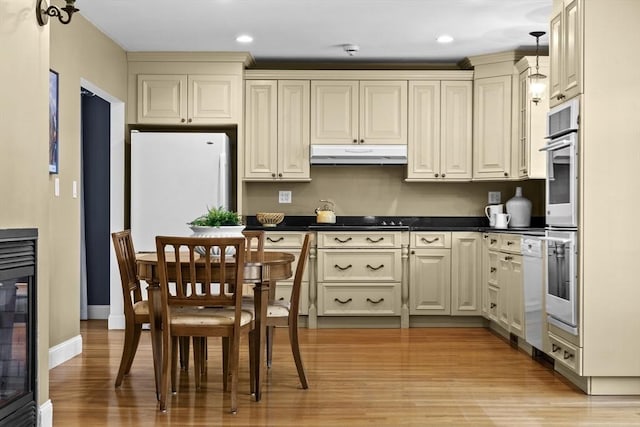61 Colonial Dr, Arlington, MA 02474 - kitchen with under cabinet range hood, cream cabinetry, dark countertops, freestanding refrigerator, and light wood-style floors