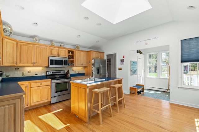 4 N Ridge Rd, Ipswich, MA 01938 - kitchen featuring appliances with stainless steel finishes, an island with sink, light wood-type flooring, a baseboard heating unit, and lofted ceiling with skylight