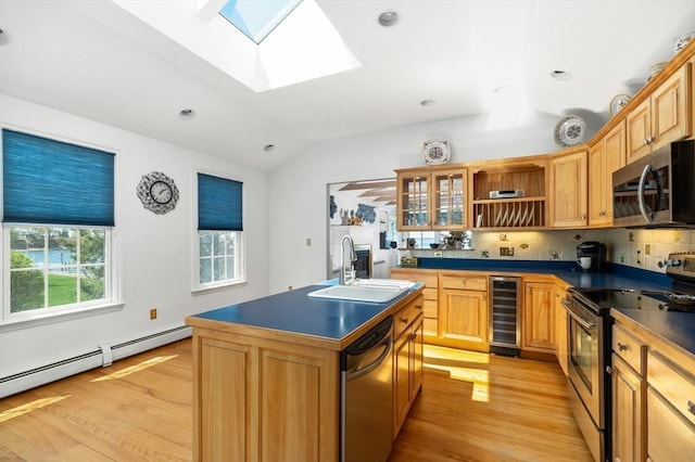 kitchen featuring wine cooler, dark countertops, vaulted ceiling with skylight, a sink, and appliances with stainless steel finishes