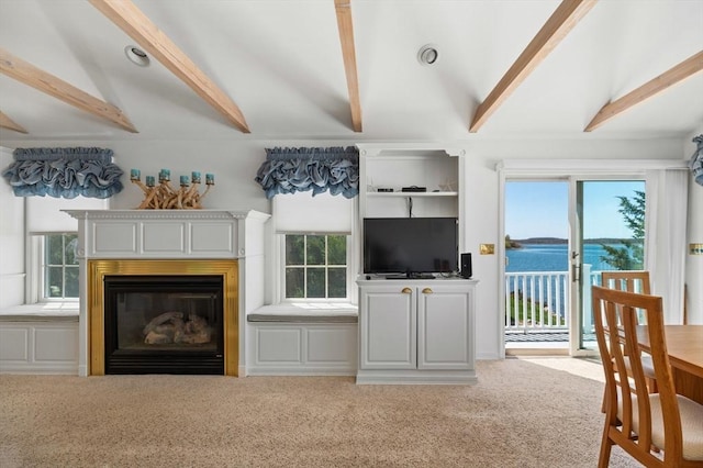 carpeted living room with lofted ceiling with beams and a glass covered fireplace