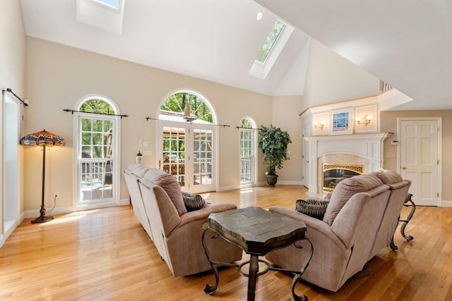 13 Lisa Ln, Georgetown, MA 01833 - living area with a skylight, high vaulted ceiling, a glass covered fireplace, light wood-type flooring, and baseboards