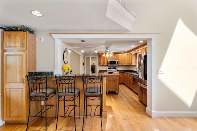 13 Lisa Ln, Georgetown, MA 01833 - kitchen featuring appliances with stainless steel finishes, a peninsula, a kitchen breakfast bar, light wood-style floors, and a ceiling fan