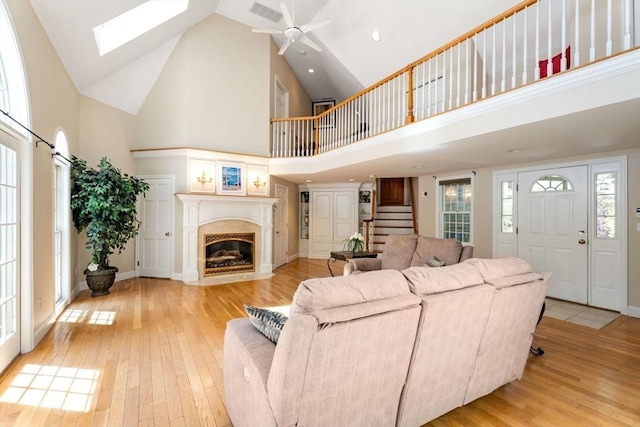 13 Lisa Ln, Georgetown, MA 01833 - living area featuring high vaulted ceiling, light wood-style flooring, stairway, a fireplace with flush hearth, and a ceiling fan