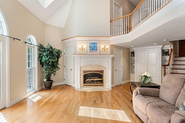 13 Lisa Ln, Georgetown, MA 01833 - living room featuring a towering ceiling, stairs, light wood-type flooring, a fireplace with flush hearth, and baseboards