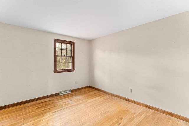 unfurnished room featuring light wood-style flooring, visible vents, and baseboards