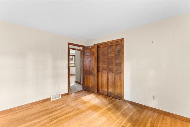 unfurnished bedroom with light wood finished floors, baseboards, visible vents, and a closet