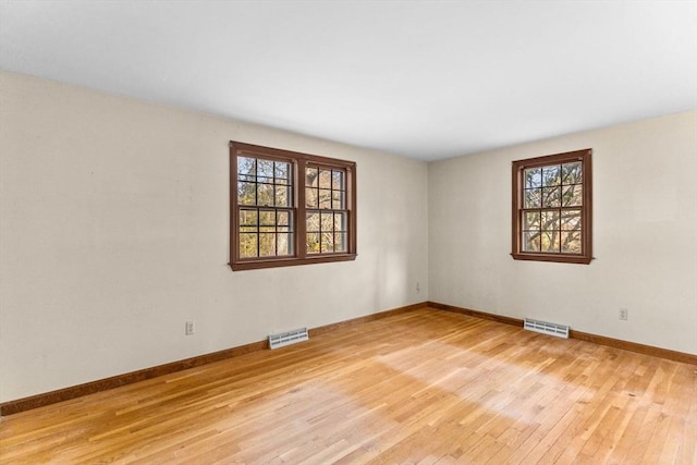 spare room featuring visible vents, light wood-style flooring, and baseboards