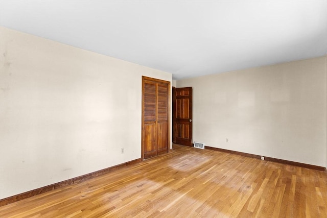 unfurnished room with light wood-type flooring, baseboards, and visible vents