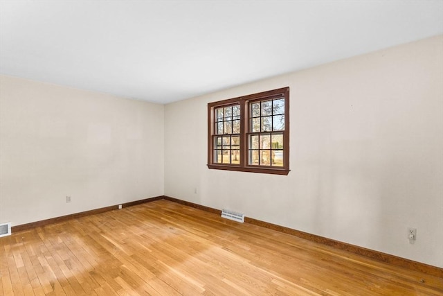 empty room with light wood-style floors, baseboards, and visible vents