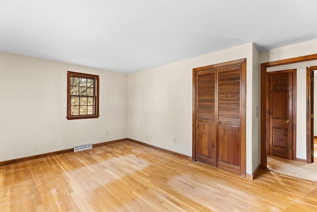 unfurnished bedroom with visible vents, a closet, light wood-style flooring, and baseboards