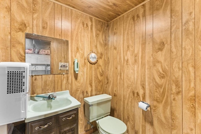 bathroom featuring toilet, wooden ceiling, wooden walls, and vanity