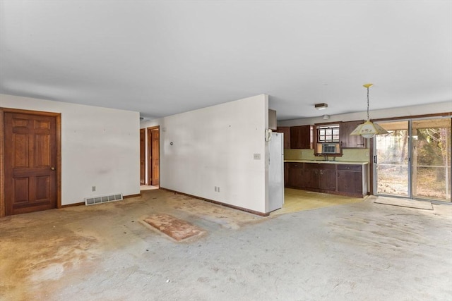 unfurnished living room featuring concrete flooring, visible vents, and baseboards