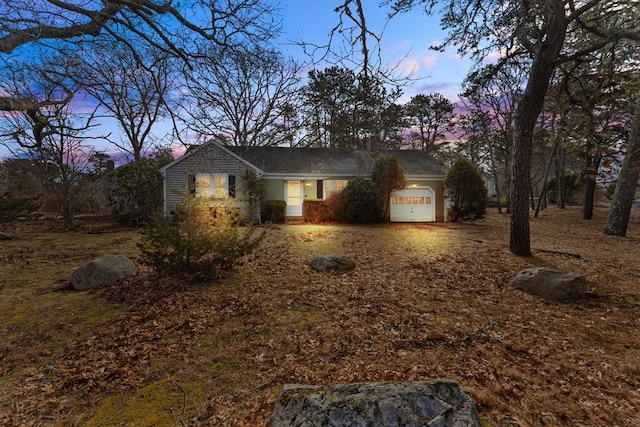 view of front of home featuring driveway, an attached garage, and a chimney