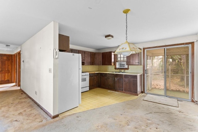 kitchen featuring pendant lighting, light countertops, dark brown cabinetry, a sink, and white appliances