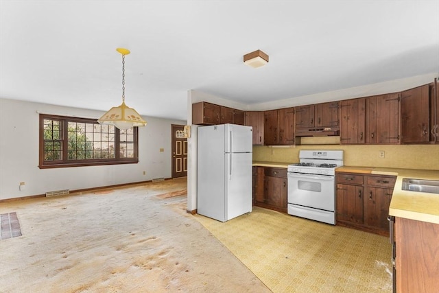 kitchen featuring light countertops, hanging light fixtures, a sink, white appliances, and under cabinet range hood