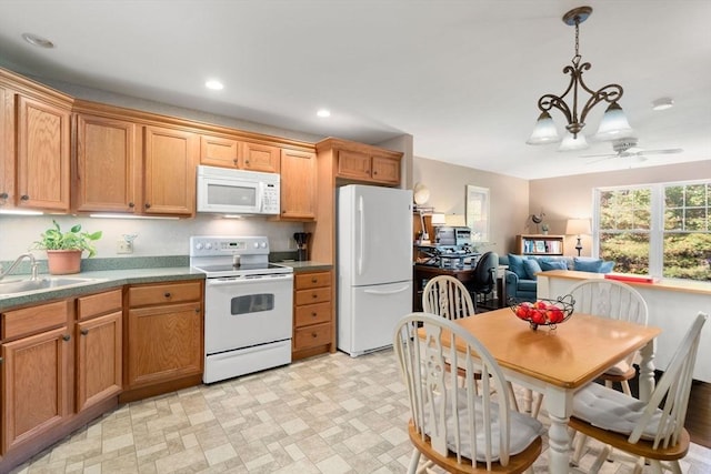 kitchen featuring white appliances, ceiling fan with notable chandelier, hanging light fixtures, and sink