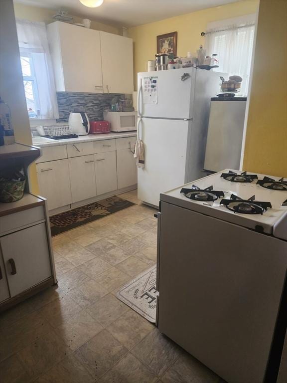 kitchen featuring light countertops, white appliances, a wealth of natural light, and tasteful backsplash