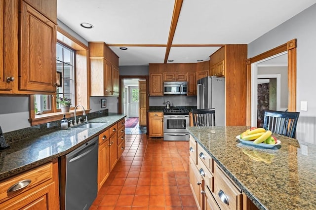 18 E St, Beverly, MA 01915 - kitchen featuring appliances with stainless steel finishes, a sink, tile patterned floors, dark stone countertops, and brown cabinets