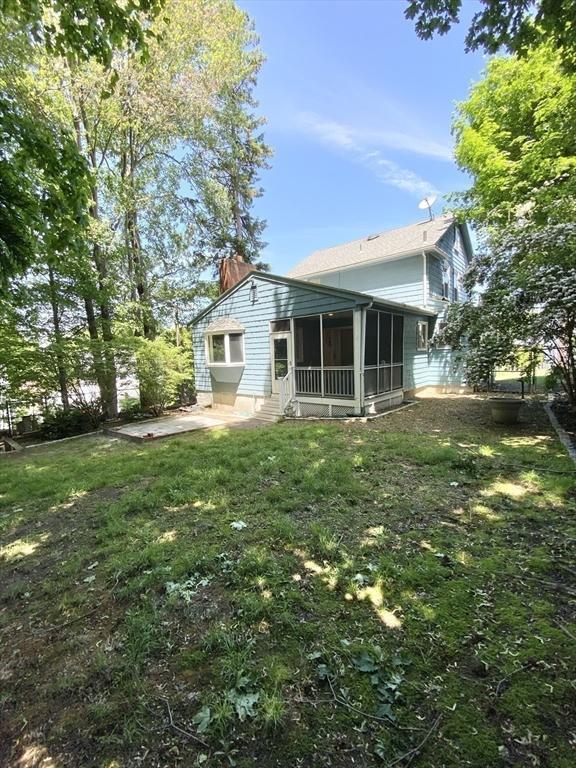 54 Hilltop St, Quincy, MA 02169 - rear view of house featuring a sunroom, a patio area, a lawn, and a chimney