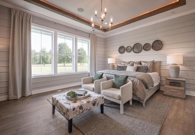 bedroom featuring hardwood / wood-style floors, a tray ceiling, and a notable chandelier