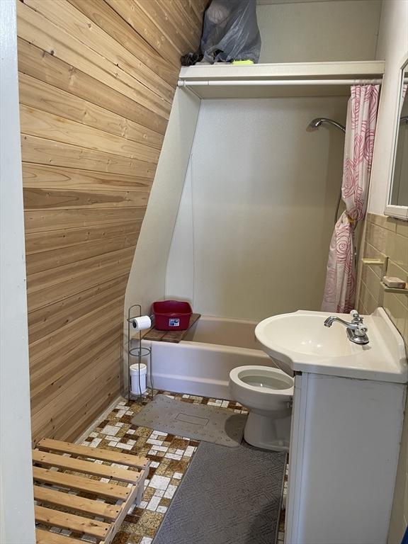 74 Newhall Unit 9, Lynn, MA 01902 - bathroom featuring wooden walls, toilet, vanity, and shower / bath combo with shower curtain