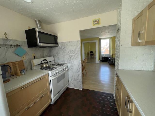 74 Newhall Unit 9, Lynn, MA 01902 - kitchen with white gas range oven, stainless steel microwave, light countertops, a textured ceiling, and tile walls