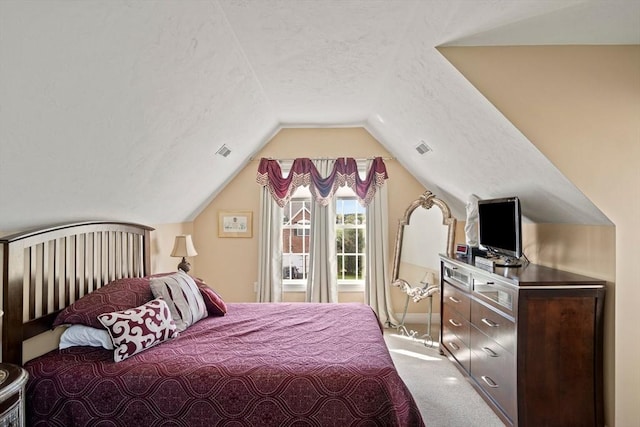 bedroom with a textured ceiling, light colored carpet, and lofted ceiling