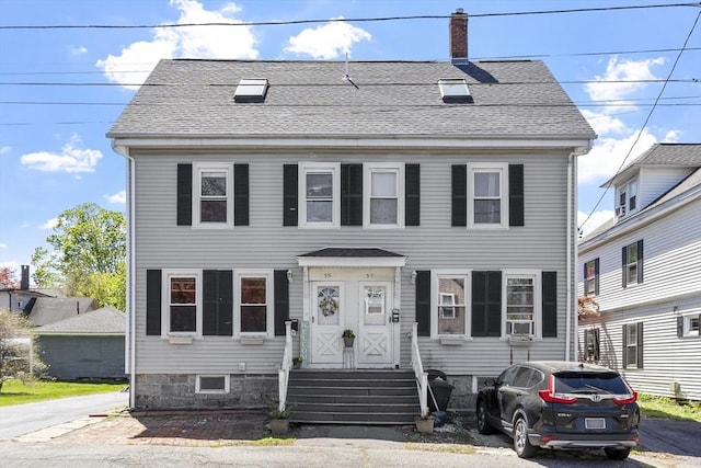colonial inspired home featuring a shingled roof and a chimney